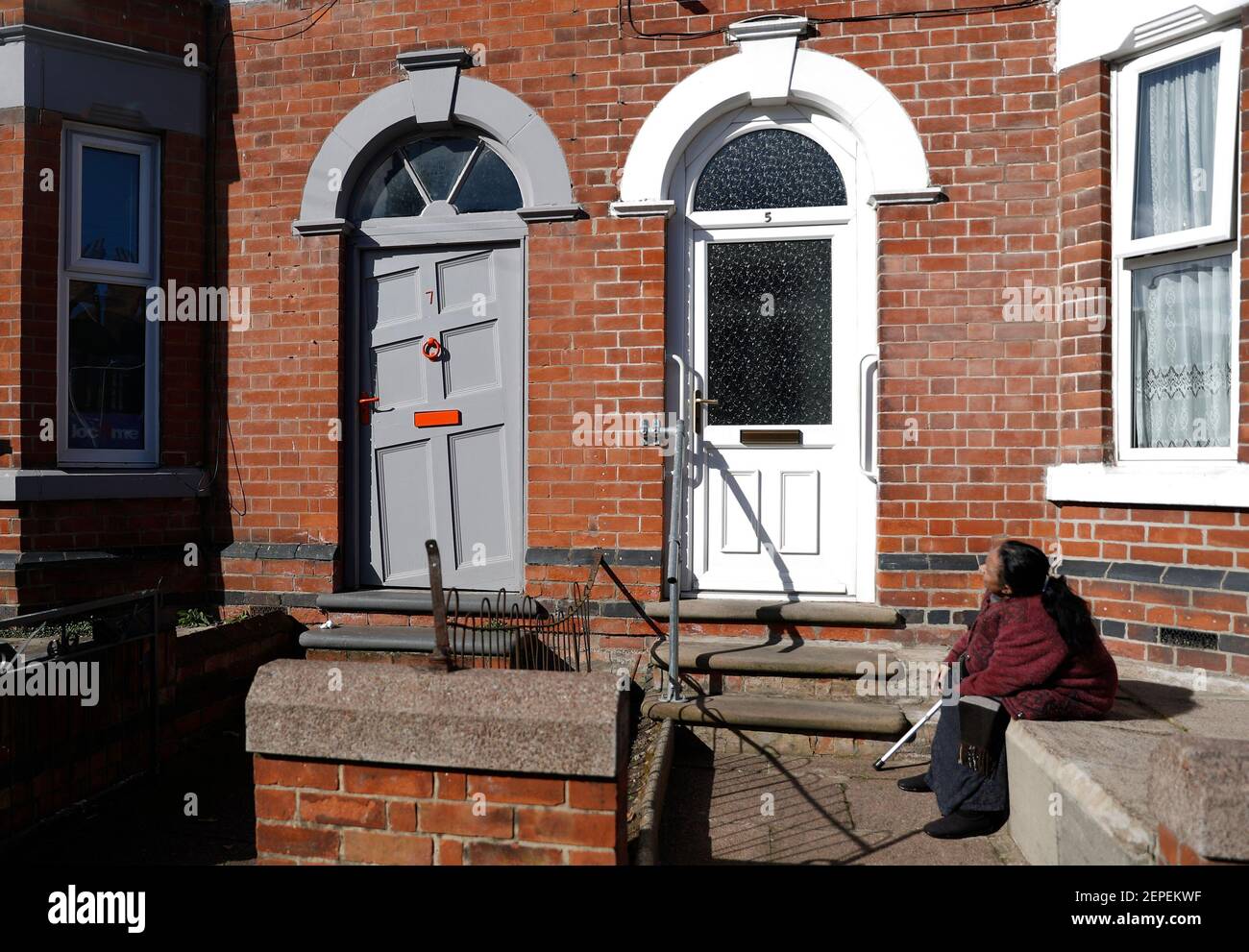 Loughborough, Leicestershire, Royaume-Uni. 27 février 2021. Une femme est assise à l'extérieur d'une maison avec une porte magnifique. Un programme de garantie hypothécaire pour aider les personnes avec de petits dépôts à obtenir sur l'échelle de propriété est prévu pour être annoncé à la semaine prochaine budget. Credit Darren Staples/Alay Live News. Banque D'Images