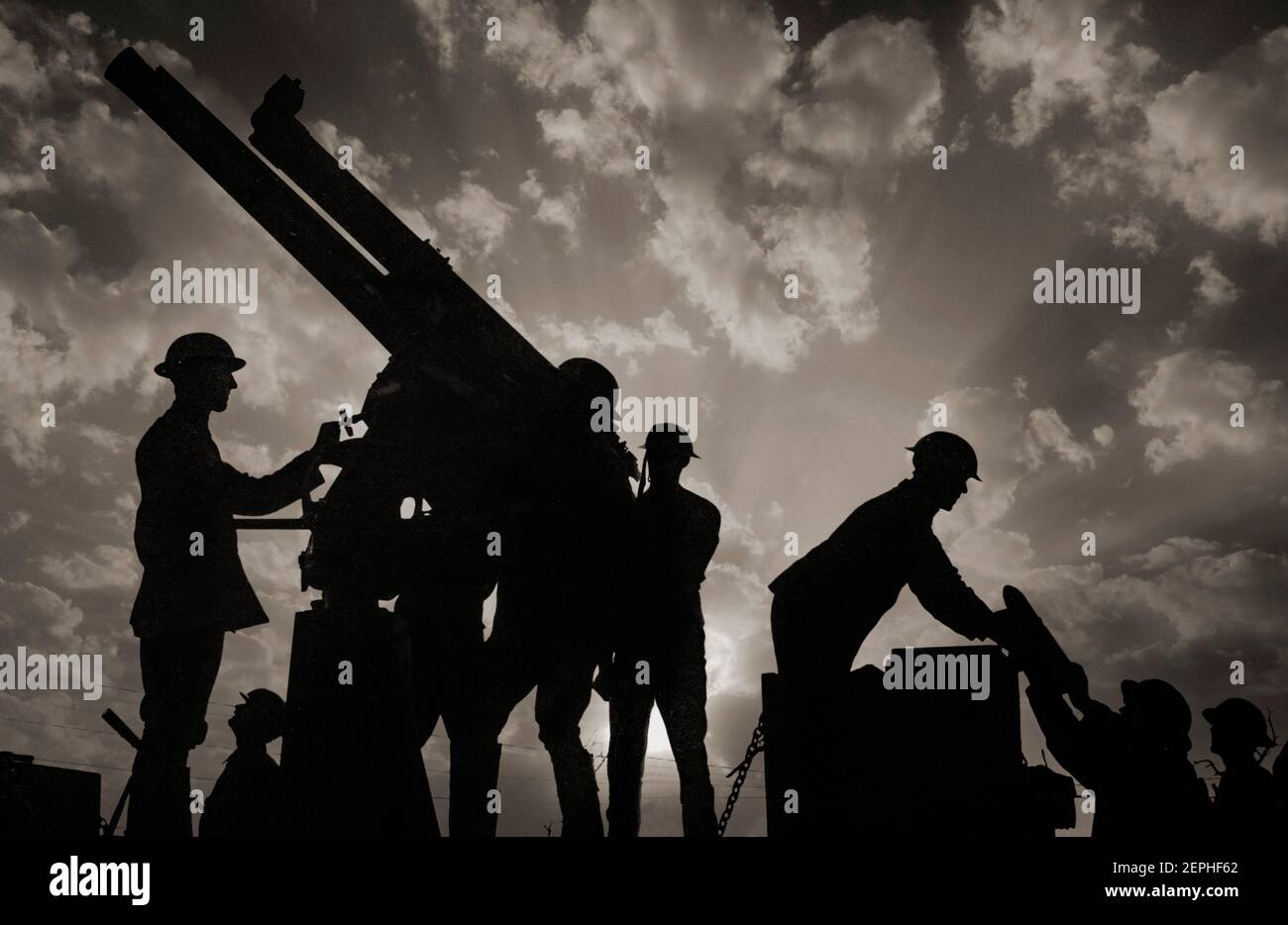 Les soldats silhouetés contre le ciel, se préparent à tirer un pistolet anti-avion. À droite de la photo, on remet un soldat une grande carapace pour le pistolet. NB : le SKY a été amélioré numériquement. Banque D'Images