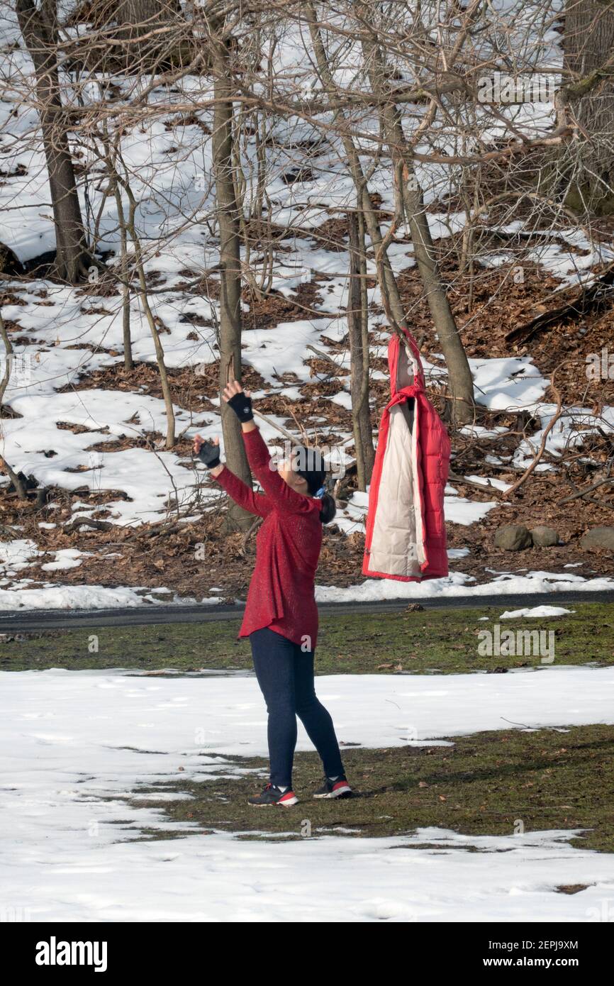 Par temps froid d'hiver, une femme asiatique américaine à un cours d'exercice de danse se réchauffe et porte sa veste sur un arbre. À Flushing, Queens, New York. Banque D'Images