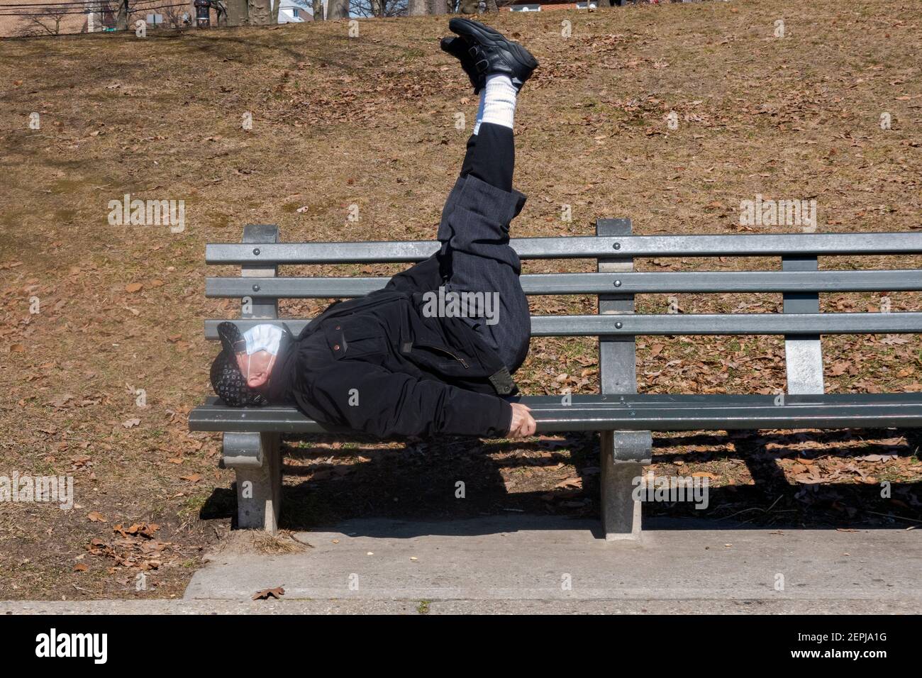 Un senior américain chinois fait des exercices d'étirement et d'estomac tout en étant allongé sur un banc à Kissena Park, Flushing, New York City. Banque D'Images