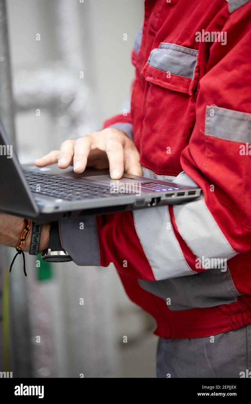 Industrie de l'énergie. Un technicien vêtu de combinaisons rouges et un casque blanc vérifiant les paramètres de chauffage. Technologie de distribution de l'eau de chauffage. Service Banque D'Images