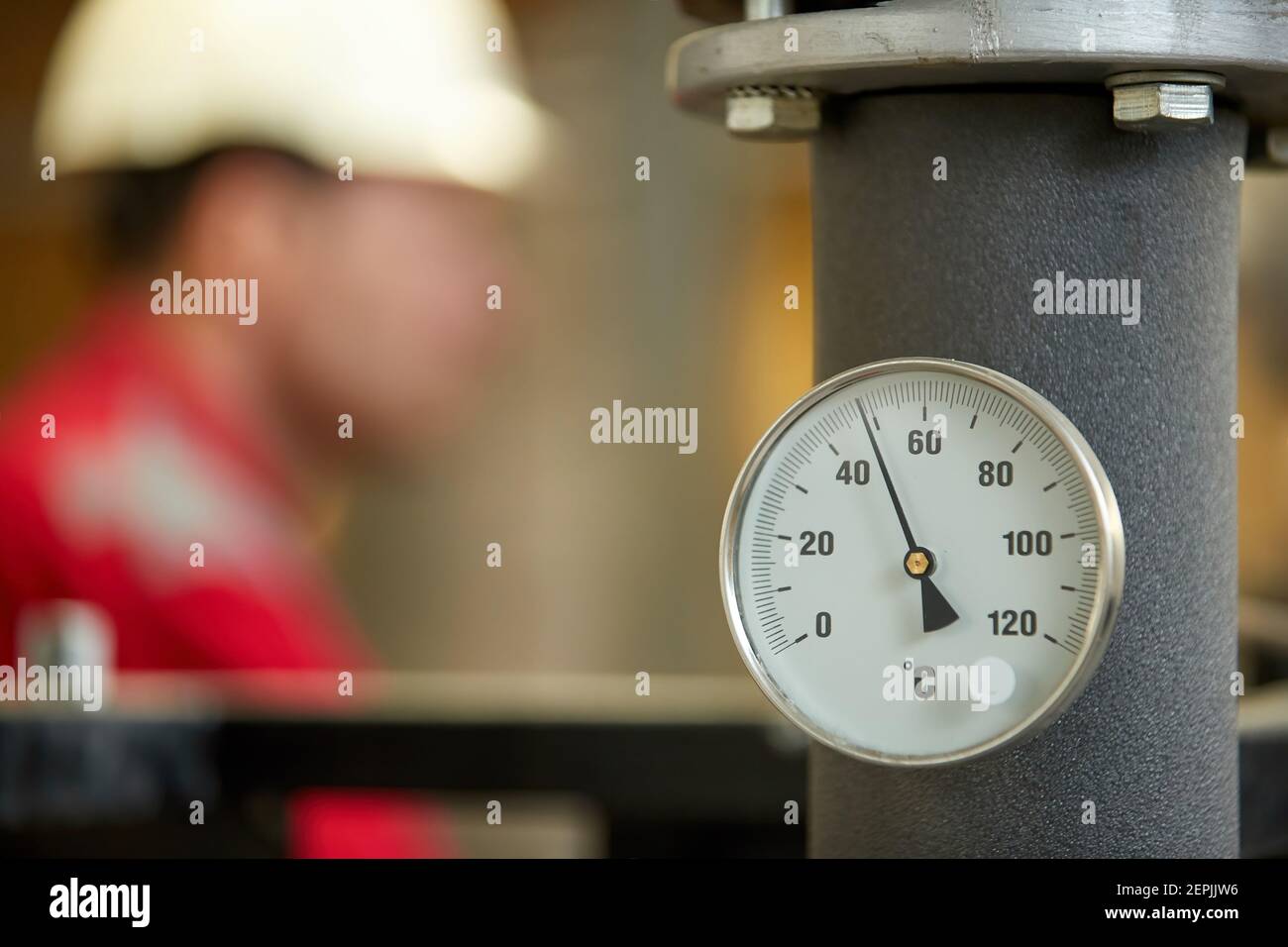 Industrie de l'énergie. Un technicien vêtu de combinaisons rouges et un casque blanc vérifiant les paramètres de chauffage. Technologie de distribution de l'eau de chauffage. Service Banque D'Images
