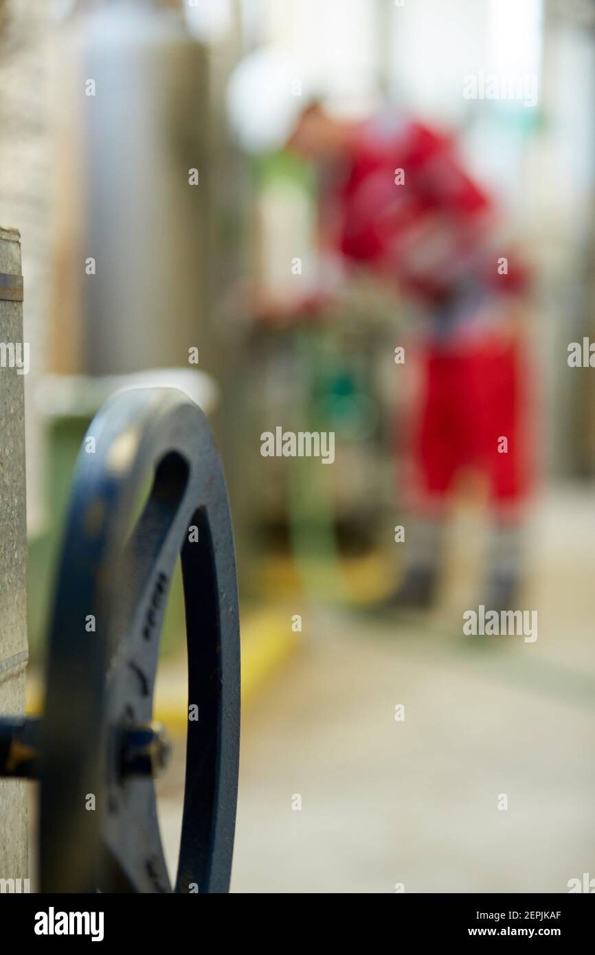 Industrie de l'énergie. Un technicien vêtu de combinaisons rouges et un casque blanc vérifiant les paramètres de chauffage. Technologie de distribution de l'eau de chauffage. Banque D'Images