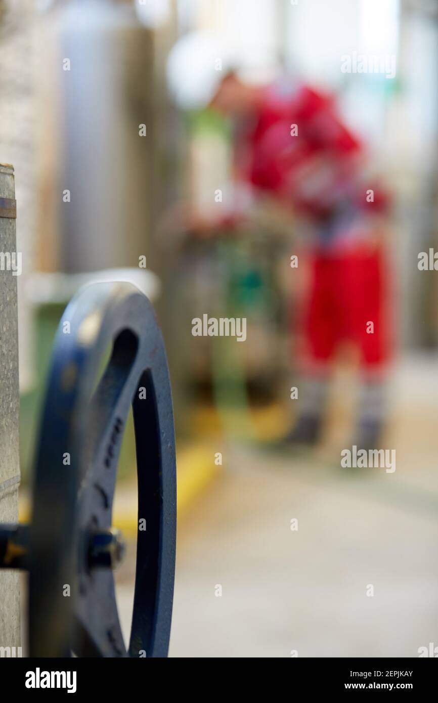 Industrie de l'énergie. Un technicien vêtu de combinaisons rouges et un casque blanc vérifiant les paramètres de chauffage. Technologie de distribution de l'eau de chauffage. Banque D'Images