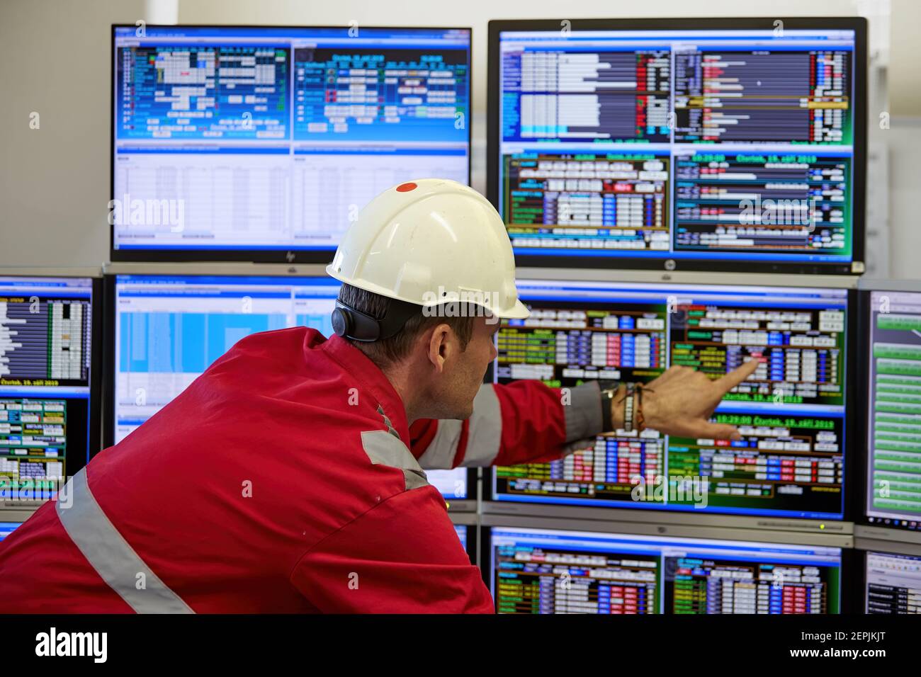 Industrie de l'énergie. Un technicien vêtu de combinaisons rouges et un casque blanc vérifiant les paramètres de chauffage. Technologie de distribution de l'eau de chauffage. Banque D'Images