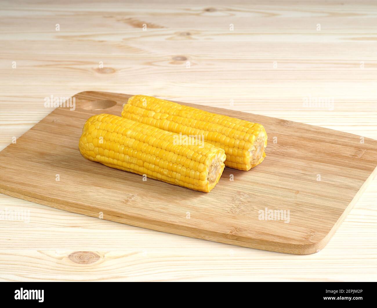 Pob de maïs bouilli et pop-corn sucré. Épis de maïs sucré cuit sur une table en bois parsemée de pop-corn. Banque D'Images