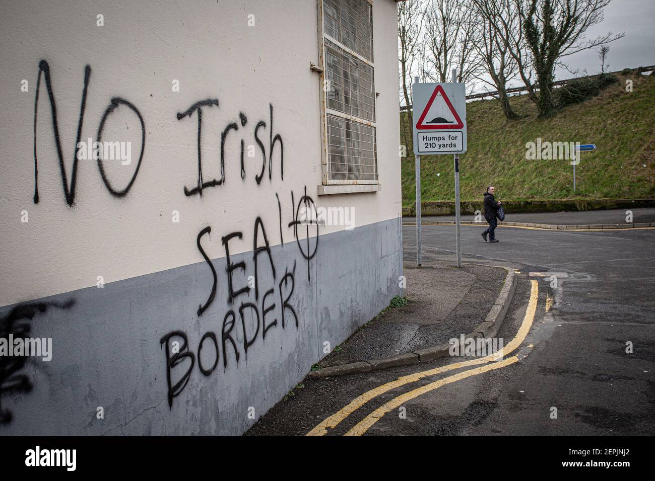 LARNE, IRLANDE DU NORD - février 24 : UN homme passe devant un graffiti loyaliste menaçant destiné au personnel portuaire de Larne, Irlande du Nord. Inspection des ports Banque D'Images