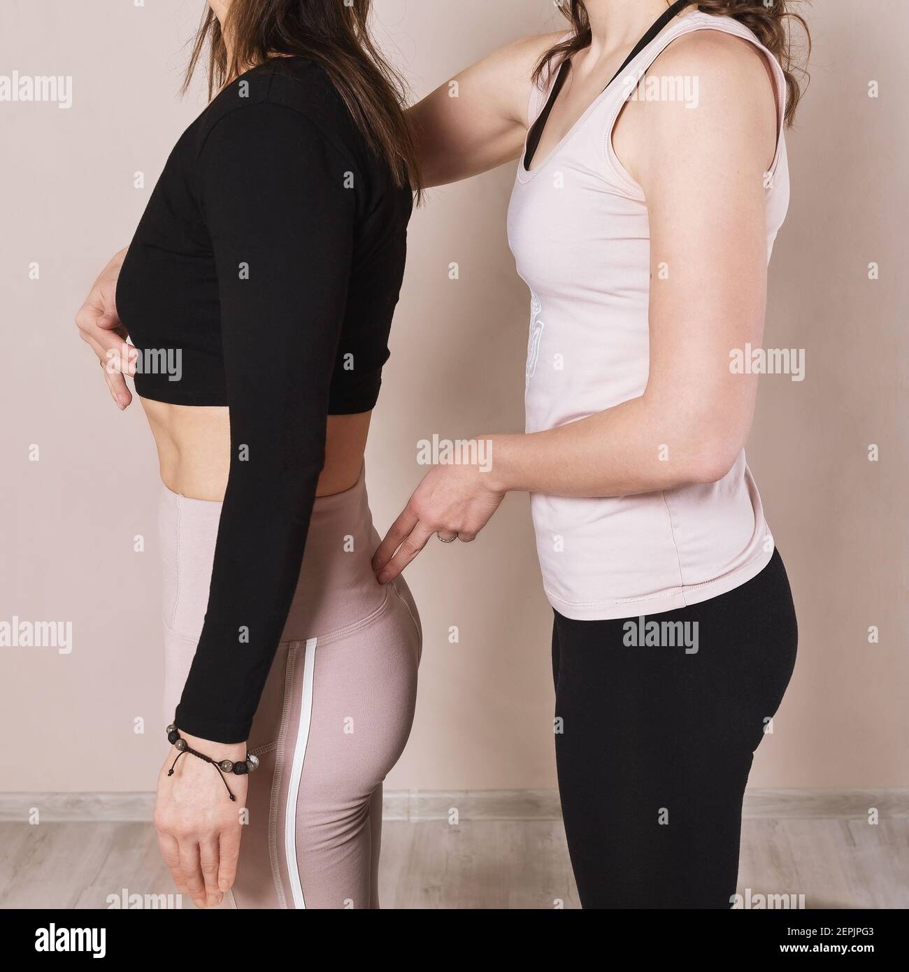 Une femme instructeur de yoga corrige un étudiant debout dans la pose Tadasana, gros plan. Banque D'Images
