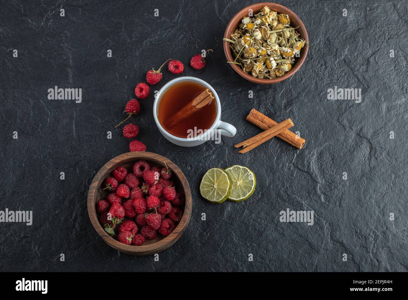 Tasse de thé aux framboises fraîches et camomille sur fond noir arrière-plan Banque D'Images