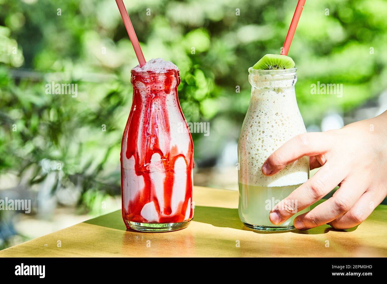 Deux milk-shakes saisis à la main sur une table en bois Banque D'Images