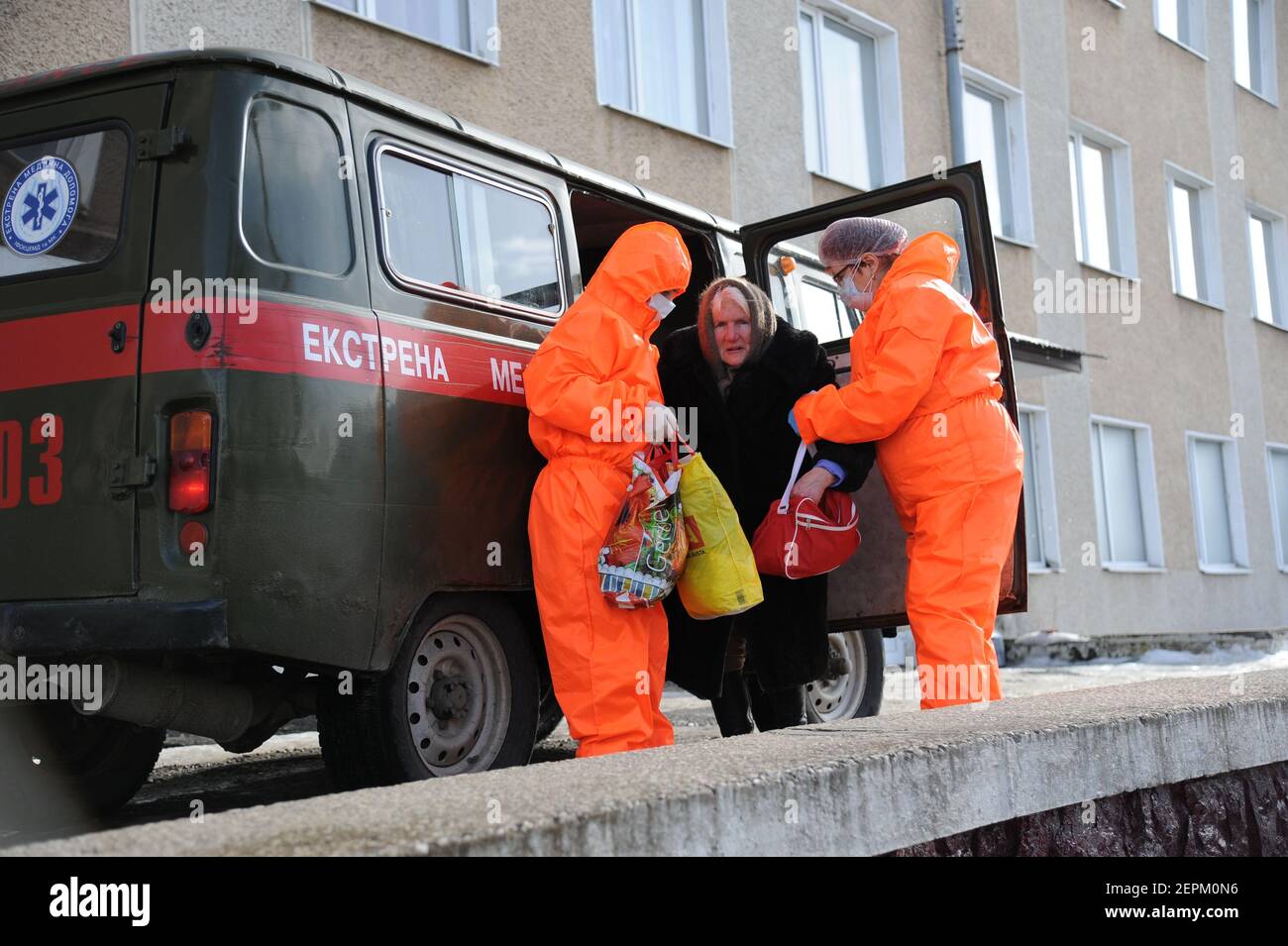 Deux travailleurs médicaux portant des combinaisons pour se protéger contre le coronavirus aident une femme âgée souffrant de COVID-19 à quitter une ambulance pour un hôpital à Bohorodchany, dans l'ouest de l'Ukraine. Après plusieurs retards, l'Ukraine a finalement reçu 500,000 doses du vaccin AstraZeneca commercialisé sous le nom de CoviShield, la première expédition de doses du vaccin Covid-19. L'Ukraine est l'une des dernières dans la région à commencer la vaccination de sa population. Banque D'Images