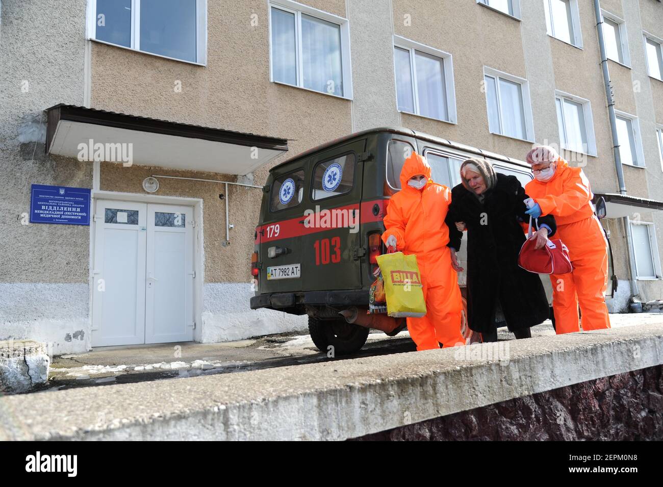 Deux travailleurs médicaux portant des combinaisons pour se protéger contre le coronavirus aident une femme âgée souffrant de COVID-19 à quitter une ambulance pour un hôpital à Bohorodchany, dans l'ouest de l'Ukraine. Après plusieurs retards, l'Ukraine a finalement reçu 500,000 doses du vaccin AstraZeneca commercialisé sous le nom de CoviShield, la première expédition de doses du vaccin Covid-19. L'Ukraine est l'une des dernières dans la région à commencer la vaccination de sa population. Banque D'Images