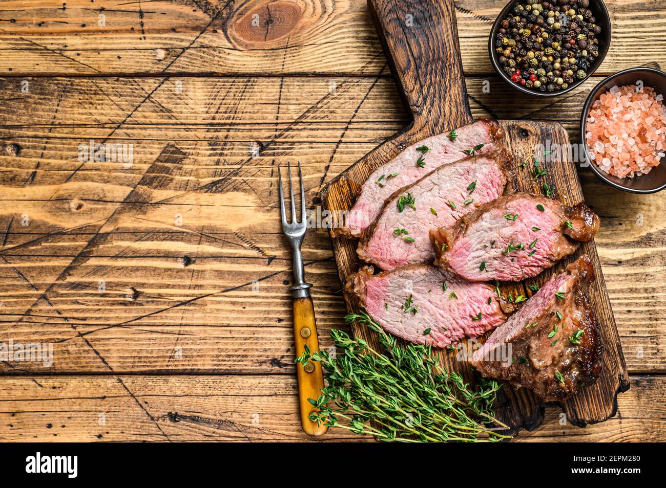 Tranches rares de rôti de boeuf sirloin à trois pointes steak bbq sur une planche à découper en bois. fond en bois. Vue de dessus. Copier l'espace Banque D'Images