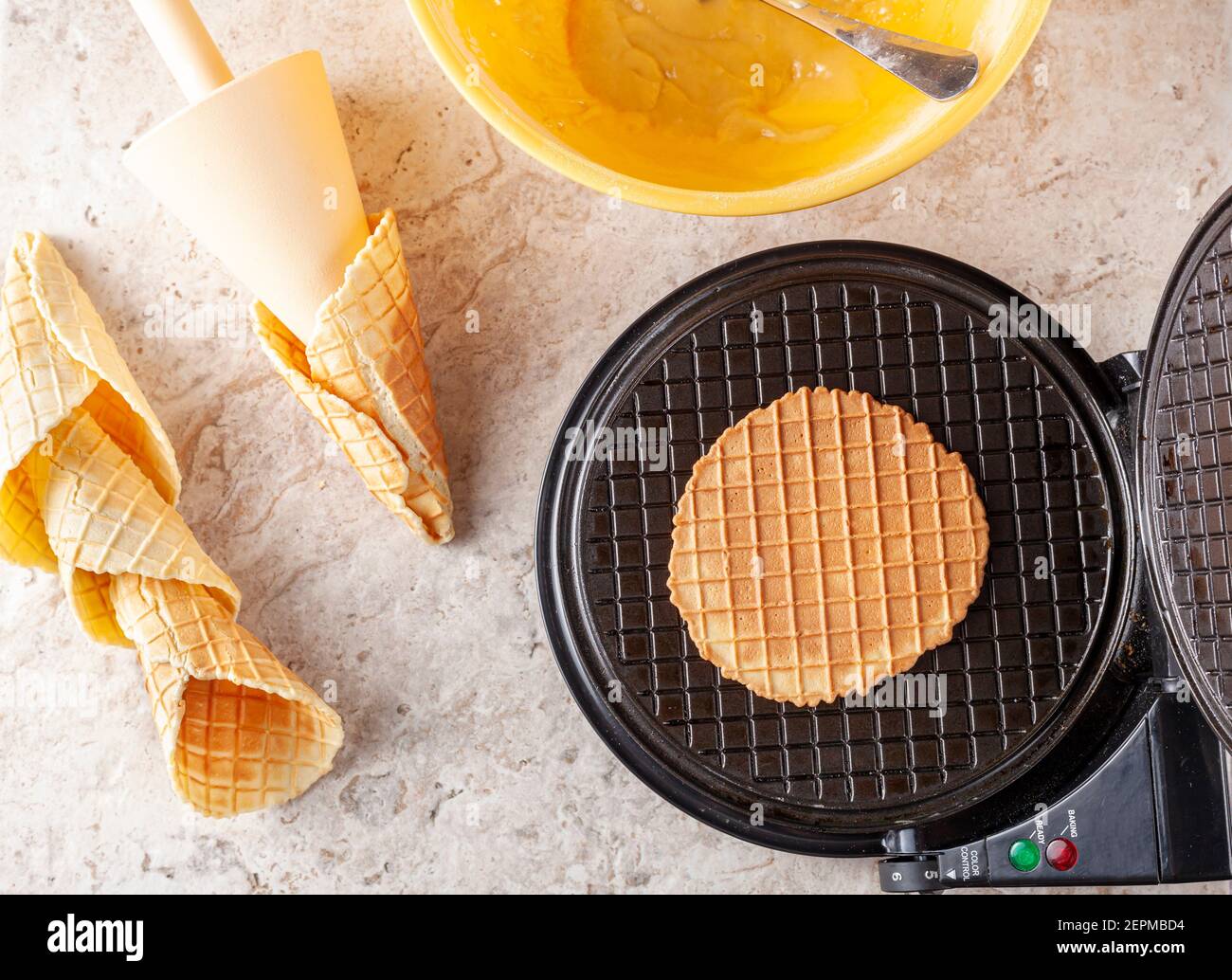 Image plate de l'appareil à gaufrer conique anti-adhésif pour faire des cornets de glace faits maison. Des cônes fraîchement roulés à la main sont posés sur un comptoir en marbre. Ingredien Banque D'Images
