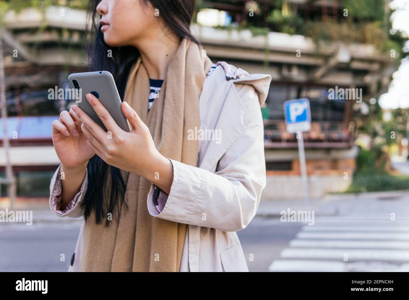 Petite femme asiatique non reconnaissable sur la rue de la ville sur un téléphone portable, en plein soleil Banque D'Images