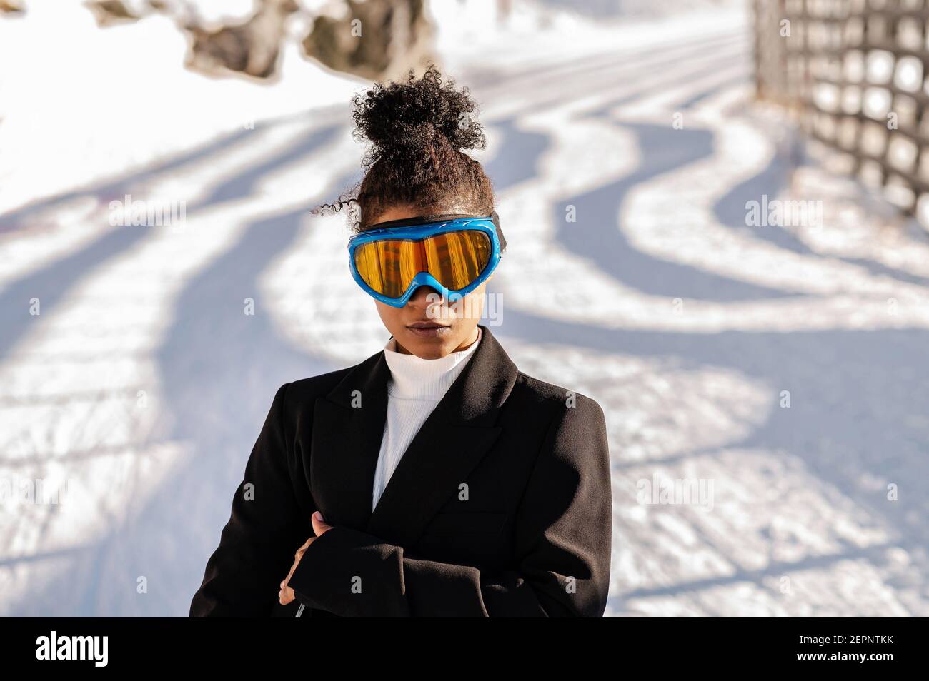 Jeune athlète ethnique élégante en lunettes de protection caméra sur route enneigée au soleil Banque D'Images