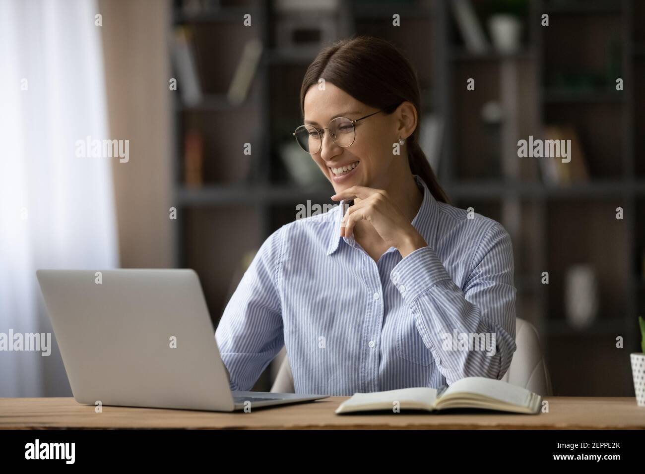 Femme souriante travaillant sur un ordinateur portable à la maison en ligne Banque D'Images