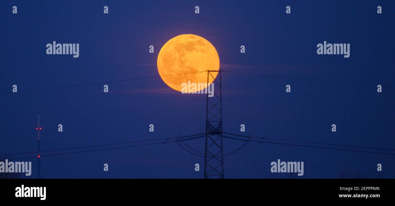 Londres, Royaume-Uni. 27 février 2021. Full Snow Moon s'élève derrière un pylône électrique dans le sud de Londres avec la tour de 219 mètres de haut de l'émetteur Crystal Palace à gauche du cadre. Crédit: Malcolm Park/Alay Banque D'Images