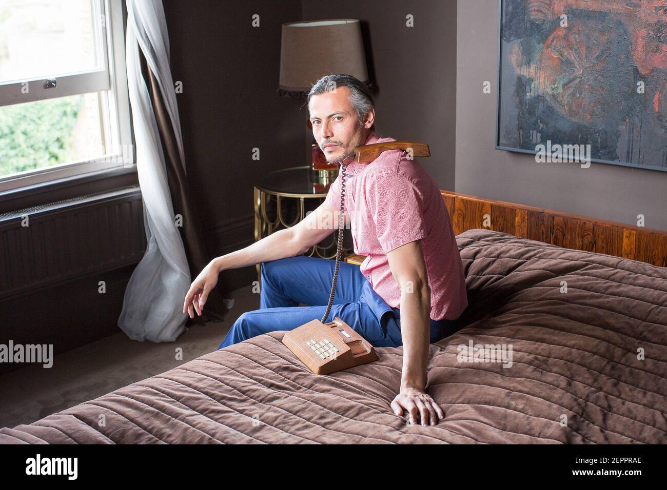 Photo de mode modèle masculin dans la suite de l'hôtel avec téléphone vintage Banque D'Images