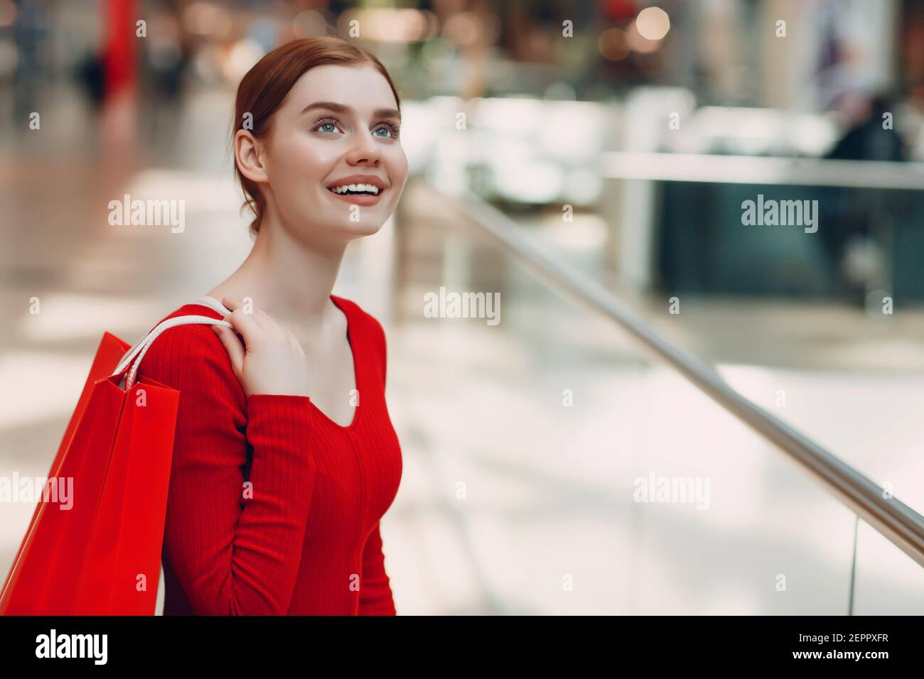 Jeune femme avec des sacs rouges en papier dans un magasin de détail Banque D'Images