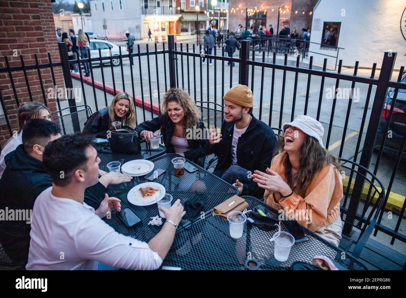 Athènes, États-Unis. 27 février 2021. Dominick Prince (à gauche), 22 ans, d'Athènes, Ohio, aime avec ses amis dans le patio à l'extérieur de la Courtside Pizza. Alors que le temps de l'Ohio réchauffe les étudiants de l'Université de l'Ohio, rendez-vous à court Street pour socialiser dans les bars. La distribution du vaccin est toujours en cours en Ohio, mais pour les étudiants qui n'interagissent pas avec de nombreuses personnes en dehors de leur cohorte, la menace de la maladie à coronavirus (COVID-19) ne les a pas empêcés de sortir pour une nuit dans la ville. Crédit : SOPA Images Limited/Alamy Live News Banque D'Images