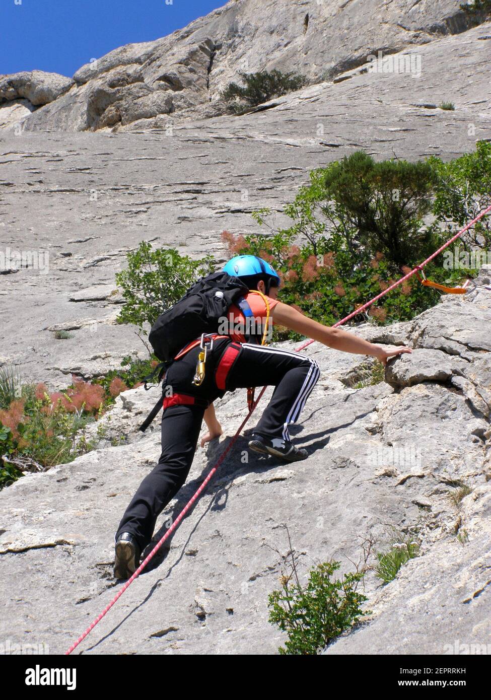 Une fille grimpeur dans un casque et de l'équipement monte le falaise Banque D'Images