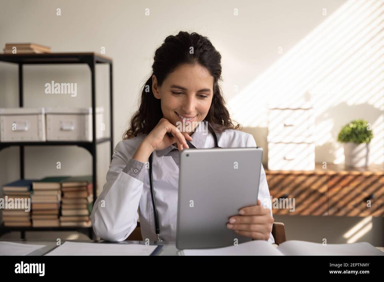 Faites un gros plan avec une femme médecin souriante en utilisant une tablette, en regardant le webinaire Banque D'Images