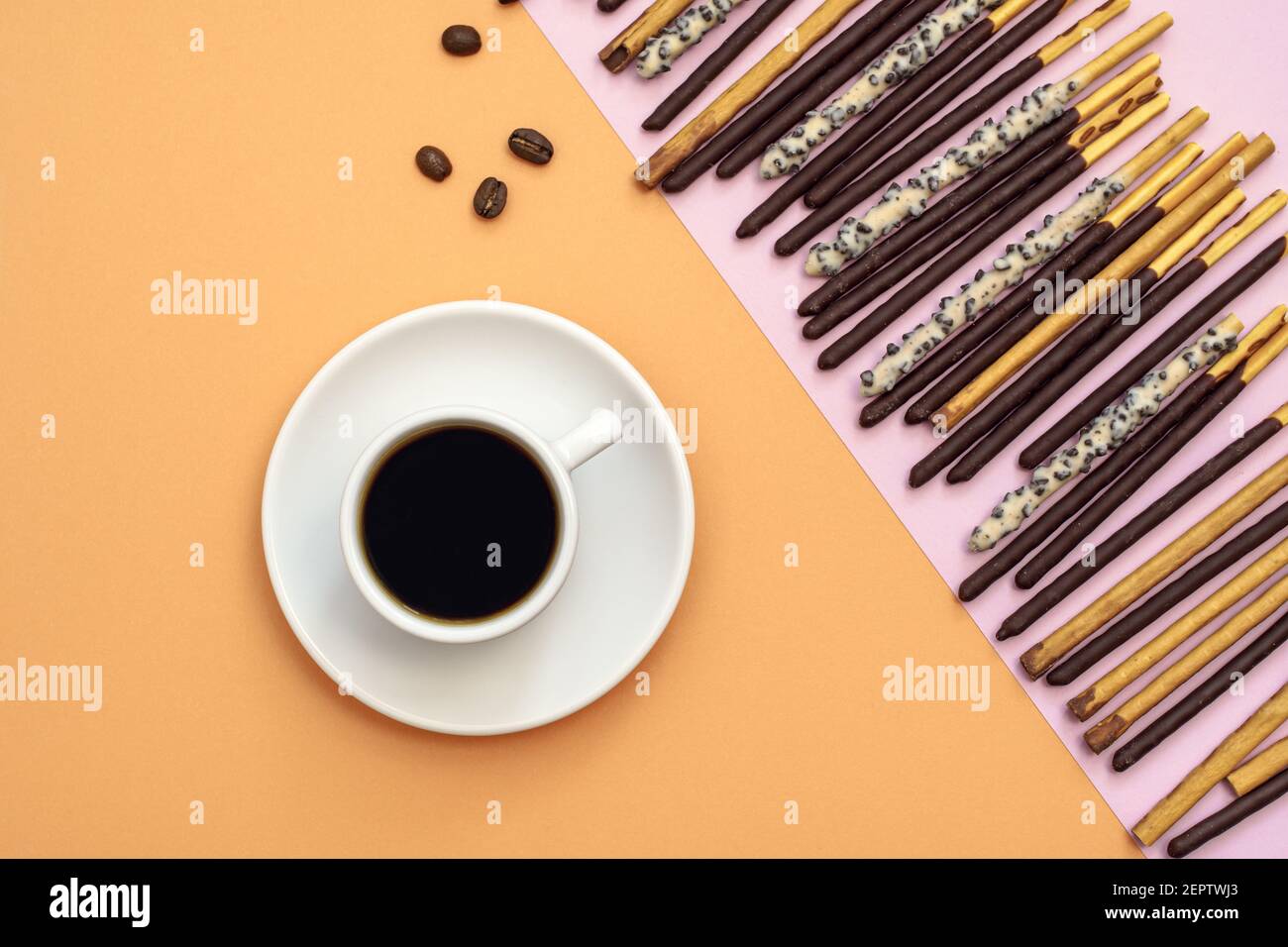 Pose plate de tasse à café noire et de bâtonnets enrobés de chocolat sur fond jaune, vue de dessus avec espace pour copier Banque D'Images