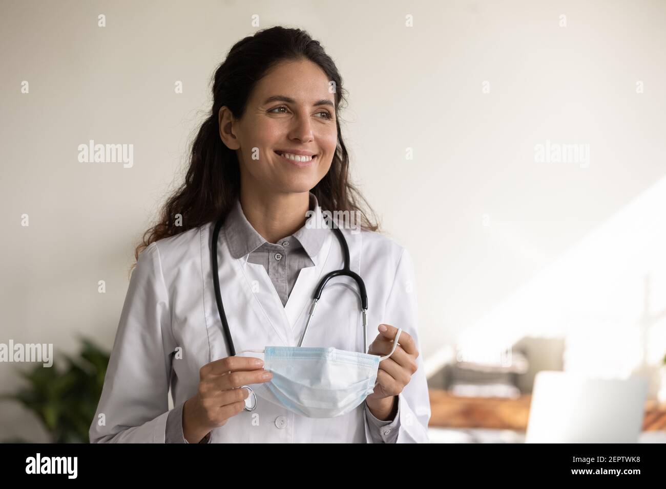 Coup de tête sourire femme médecin tenant un masque médical Banque D'Images