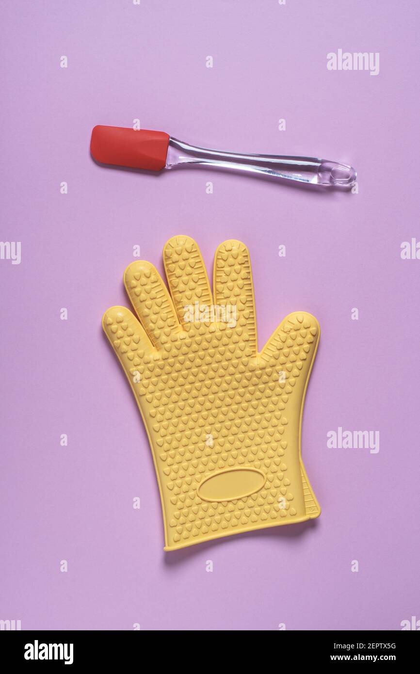 Spatule de cuisine en silicone et gant résistant à la chaleur sur fond rose. Concept de cuisine abstrait. Flat lay, vue de dessus avec espace de copie Banque D'Images