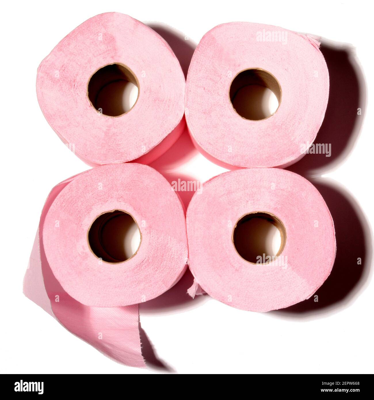 Quatre rouleaux de papier toilette rose disposés dans un carré sur un fond contrasté avec des effets d'ombre doux Banque D'Images