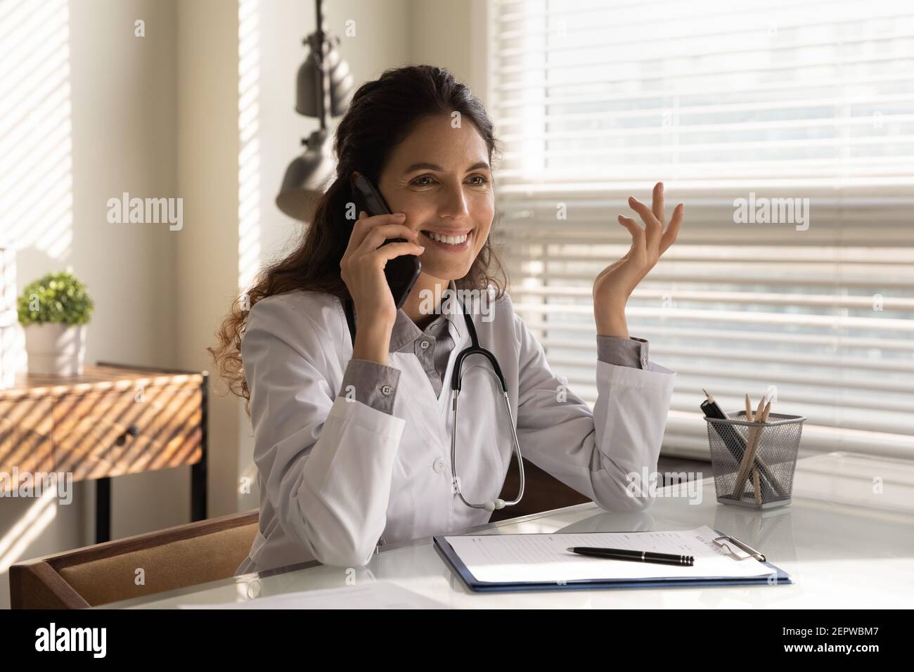 Femme souriante médecin professionnel parlant au téléphone, consultant le patient Banque D'Images
