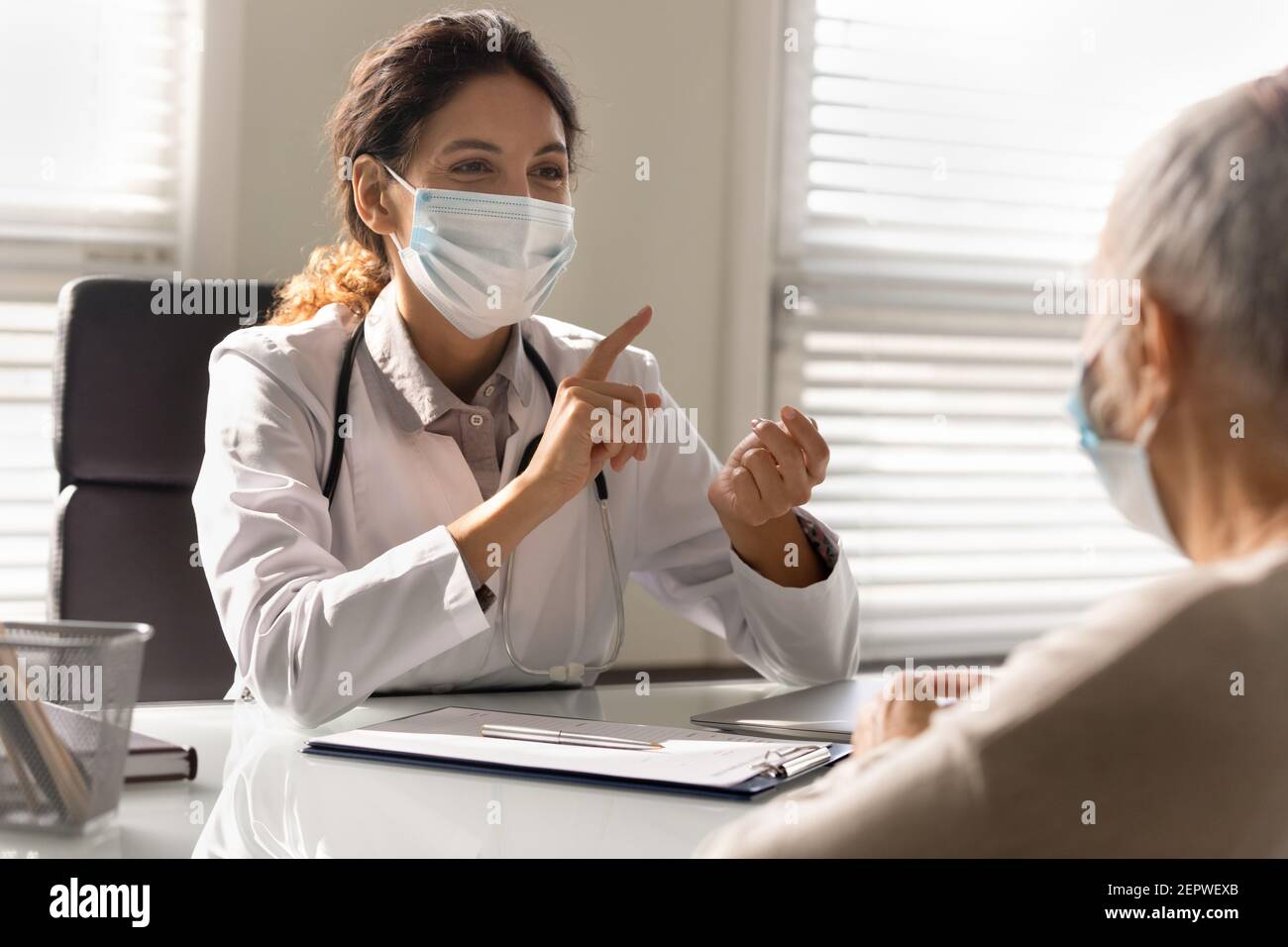 Gros plan sourire médecin portant un masque facial consultant patient mature Banque D'Images