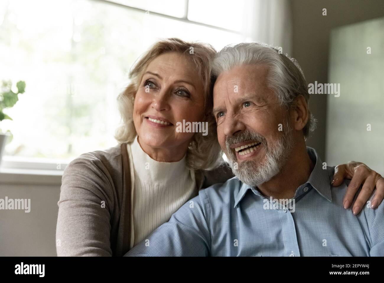 Couple de retraités âgés et pensifs qui regarde loin et souriant Banque D'Images