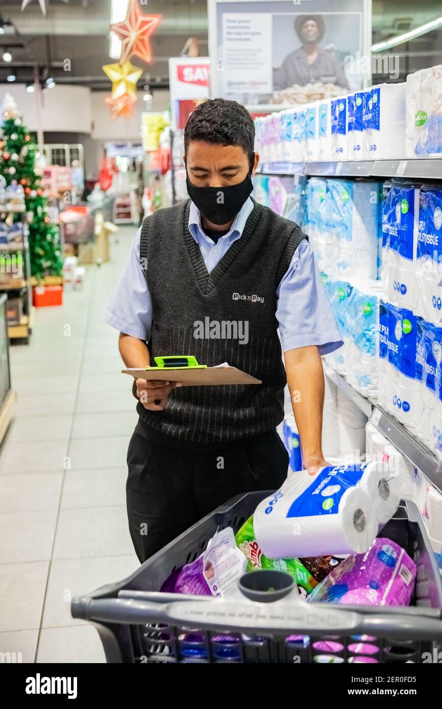 Cape Town, Afrique du Sud - 10 décembre 2020 : membre du personnel qui cueille les produits d'épicerie de l'étagère pour un service de livraison express à domicile au service local Pick n Pay su Banque D'Images