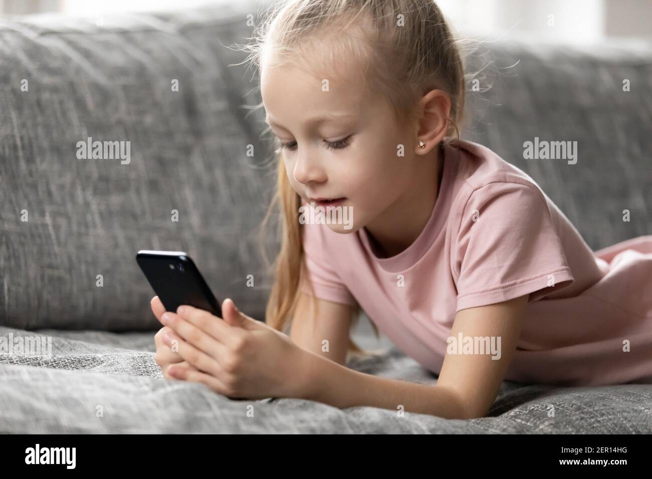 Enfant jeune fille de pré-chooler focalisée reposant sur un canapé à la maison Banque D'Images