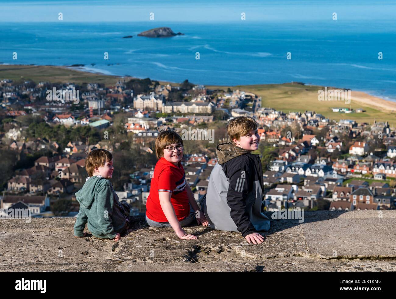 North Berwick, East Lothian, Écosse, Royaume-Uni, 28 février 2021.Escalade de la loi de Berwick pour le syndrome de Rett : le jour des maladies rares, Nina McKinney, âgée de 7 ans, atteint son objectif de gravir la colline de 613 pieds chaque jour ce mois-ci afin de recueillir des fonds pour l'organisme de bienfaisance Reverse Rett, qui soutient la recherche sur le trouble dont souffre sa sœur.Nina a bravé tout le temps pendant le mois de février et heureusement aujourd'hui soleil.Photo: Nina avec ses deux frères Angus, 11 ans et Felix, 4 ans profiter de la vue sur North Berwick Banque D'Images