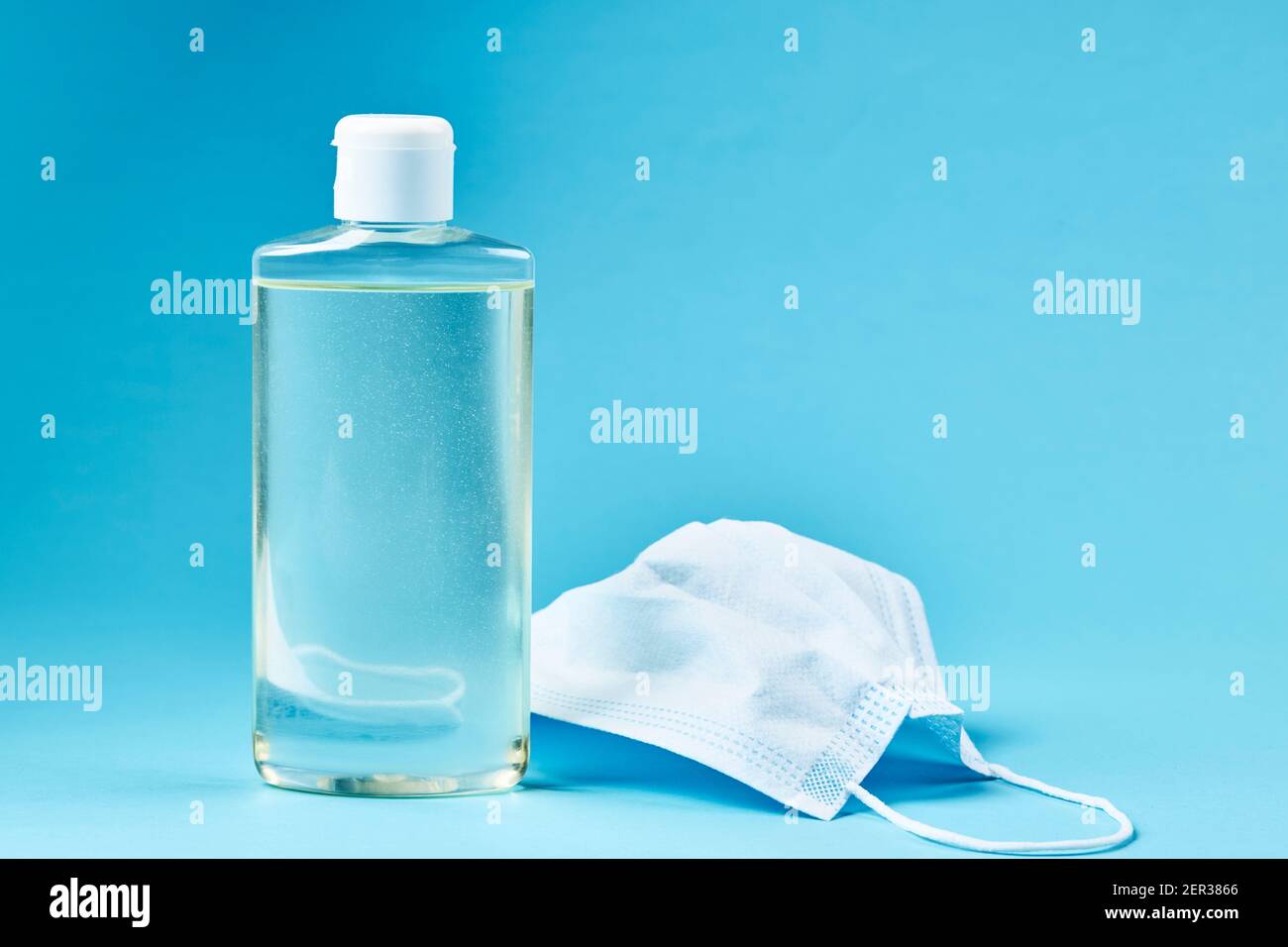 désinfectant pour les mains vierge avec masque sur fond bleu. espace de copie. concept de symbole covid-19 Banque D'Images