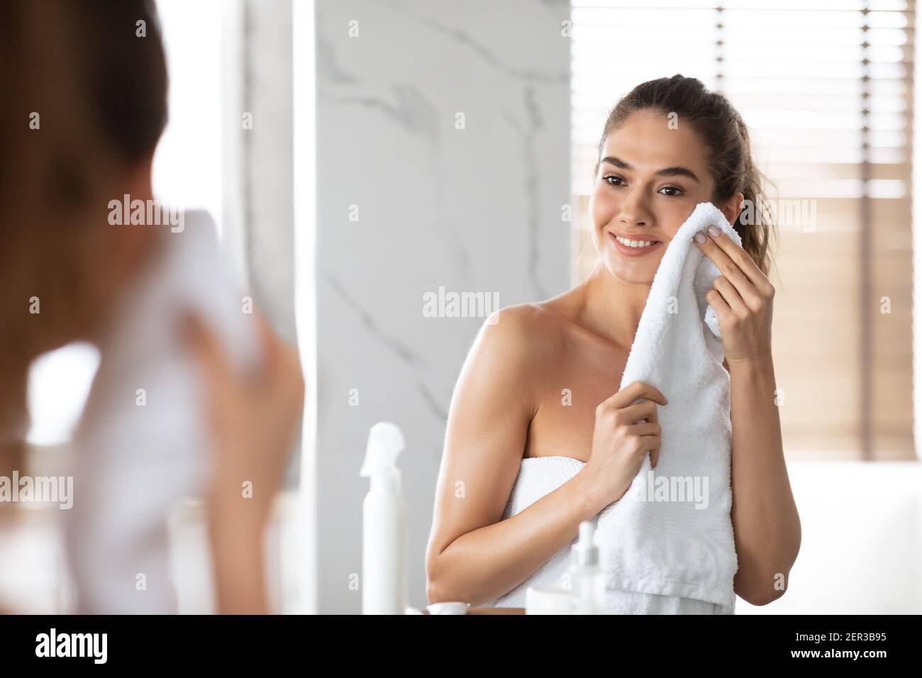 Femme séchant visage propre avec serviette après lavage dans la salle de bains Banque D'Images