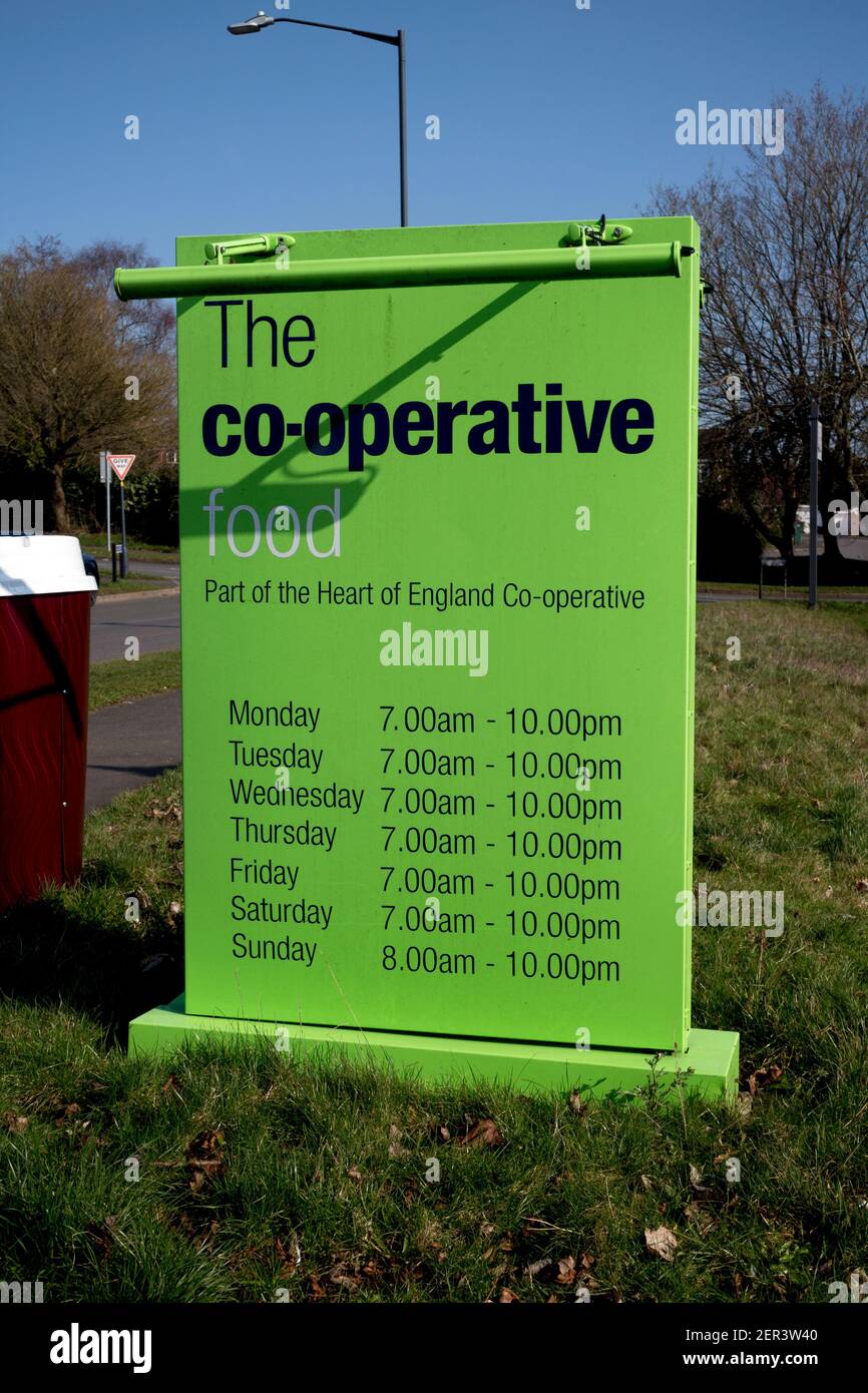 Un panneau indiquant les heures d'ouverture d'un mini-supermarché Co-operative Food, Woodloes Park Estate, Warwick, Royaume-Uni Banque D'Images
