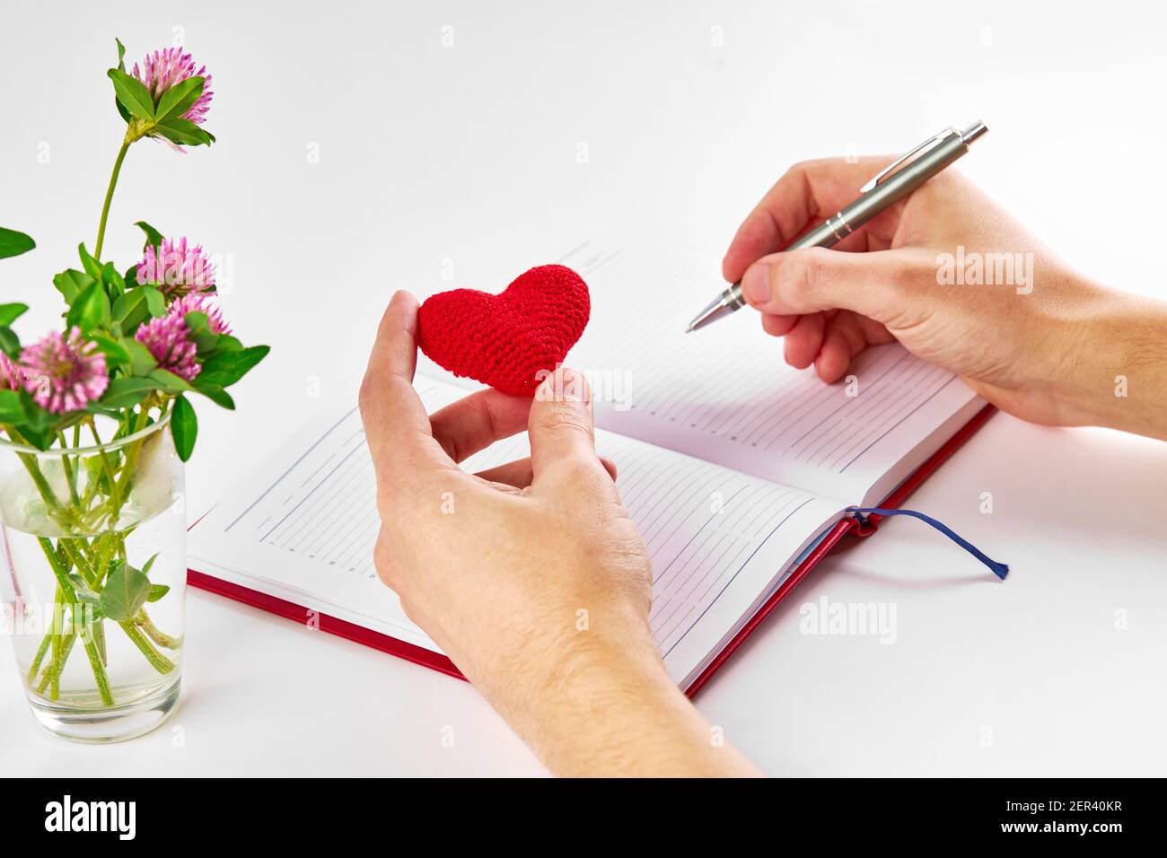personne caucasienne prenant des notes à la laiterie et tenant le coeur rouge à son bras sur fond blanc. l'été romantique notes concept Banque D'Images