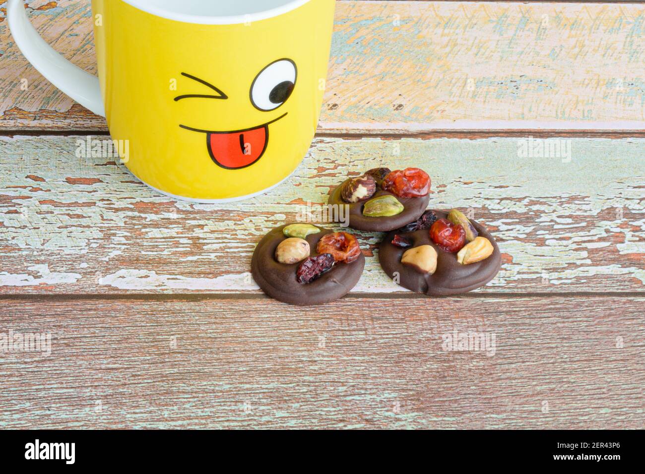 Biscuits aux pépites de chocolat avec noix à côté d'une tasse de lait jaune. Banque D'Images