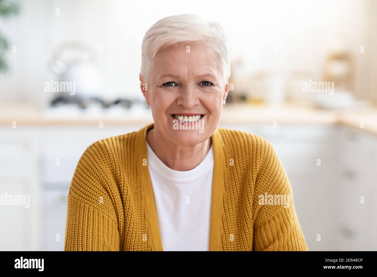 Portrait d'une femme âgée heureuse assise dans la cuisine Banque D'Images