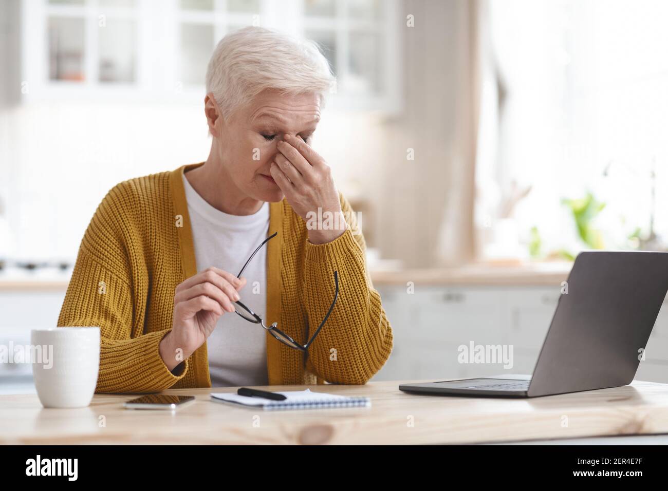 Femme mature fatiguée freelance travaillant à la maison, en utilisant un ordinateur portable Banque D'Images
