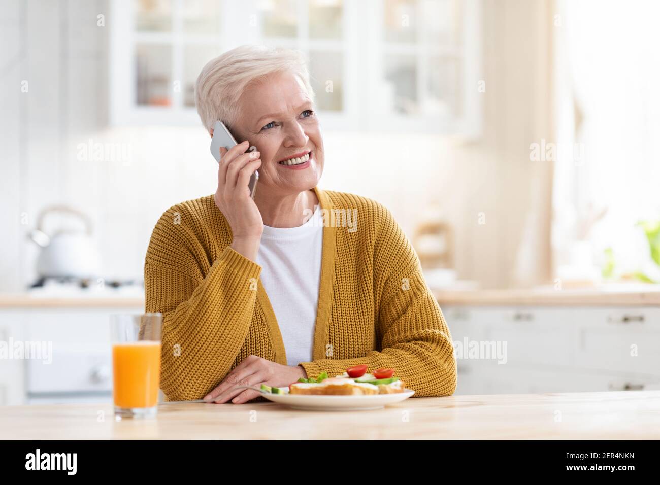 Belle femme âgée déjeuner et parler au téléphone Banque D'Images
