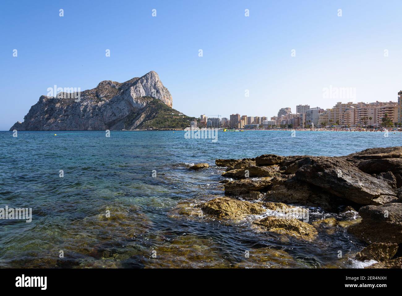 Vue depuis les rochers de la côte avec la plage urbaine de Calpe et le crag en arrière-plan, Alicante, Espagne Banque D'Images