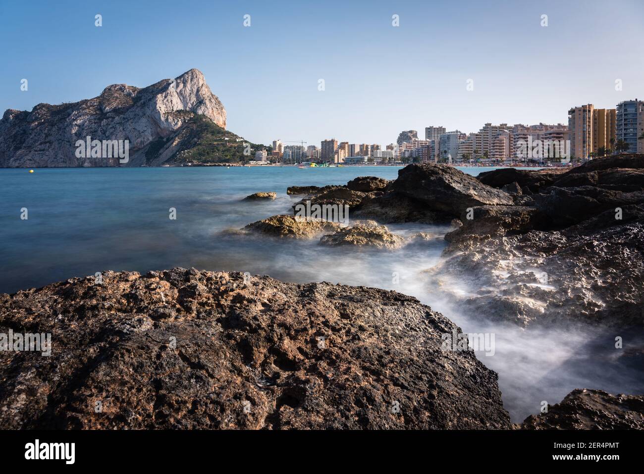 Vue depuis les rochers de la côte avec la plage urbaine de Calpe et le crag en arrière-plan, Alicante, Espagne Banque D'Images