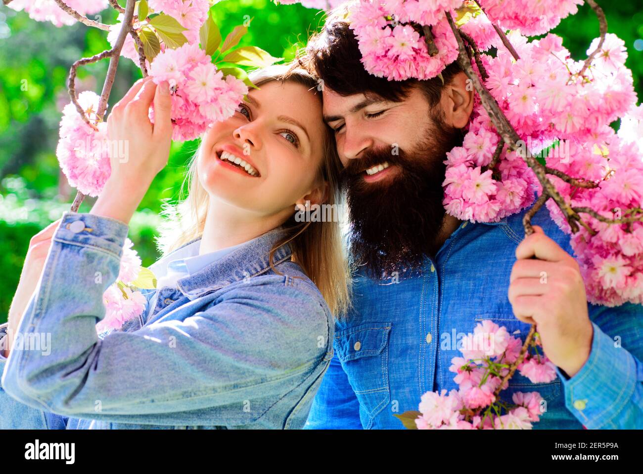 Couple de printemps près de l'arbre de sakura. Une famille heureuse dans un jardin fleuri. Banque D'Images
