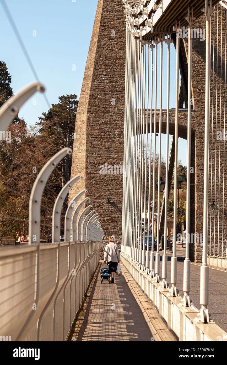 Bristol, Royaume-Uni 04-17-2010: Une femme âgée marche seule avec des sacs de shopping sur le sentier du pont suspendu Clifton qui traverse la rivière Avon Banque D'Images