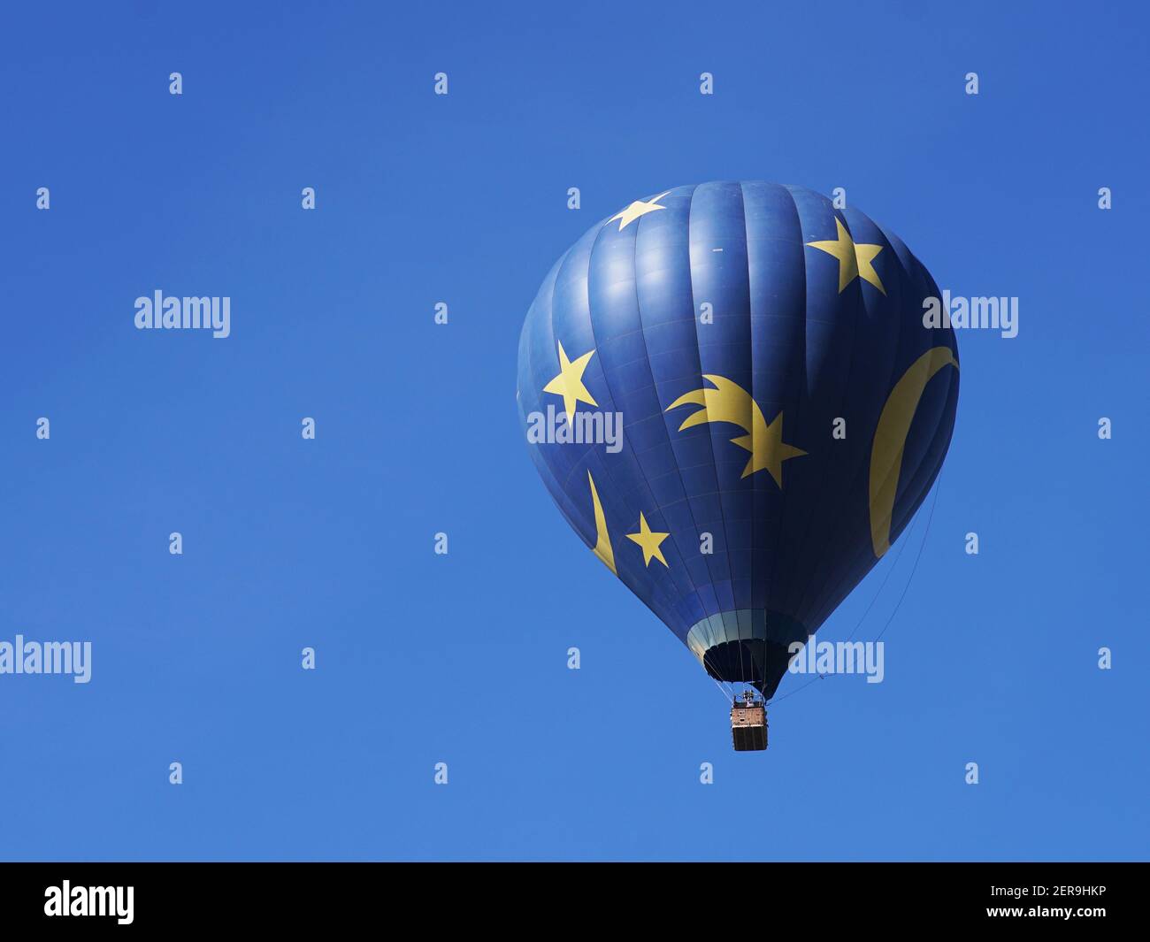 Gros plan d'une montgolfière bleue et jaune sur fond de ciel bleu et de collines. Vue latérale. Banque D'Images